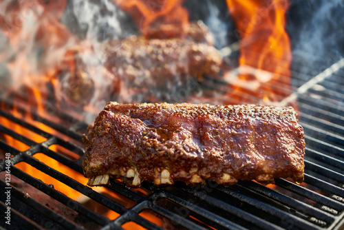 grilling baby back pork ribs over flaming grill