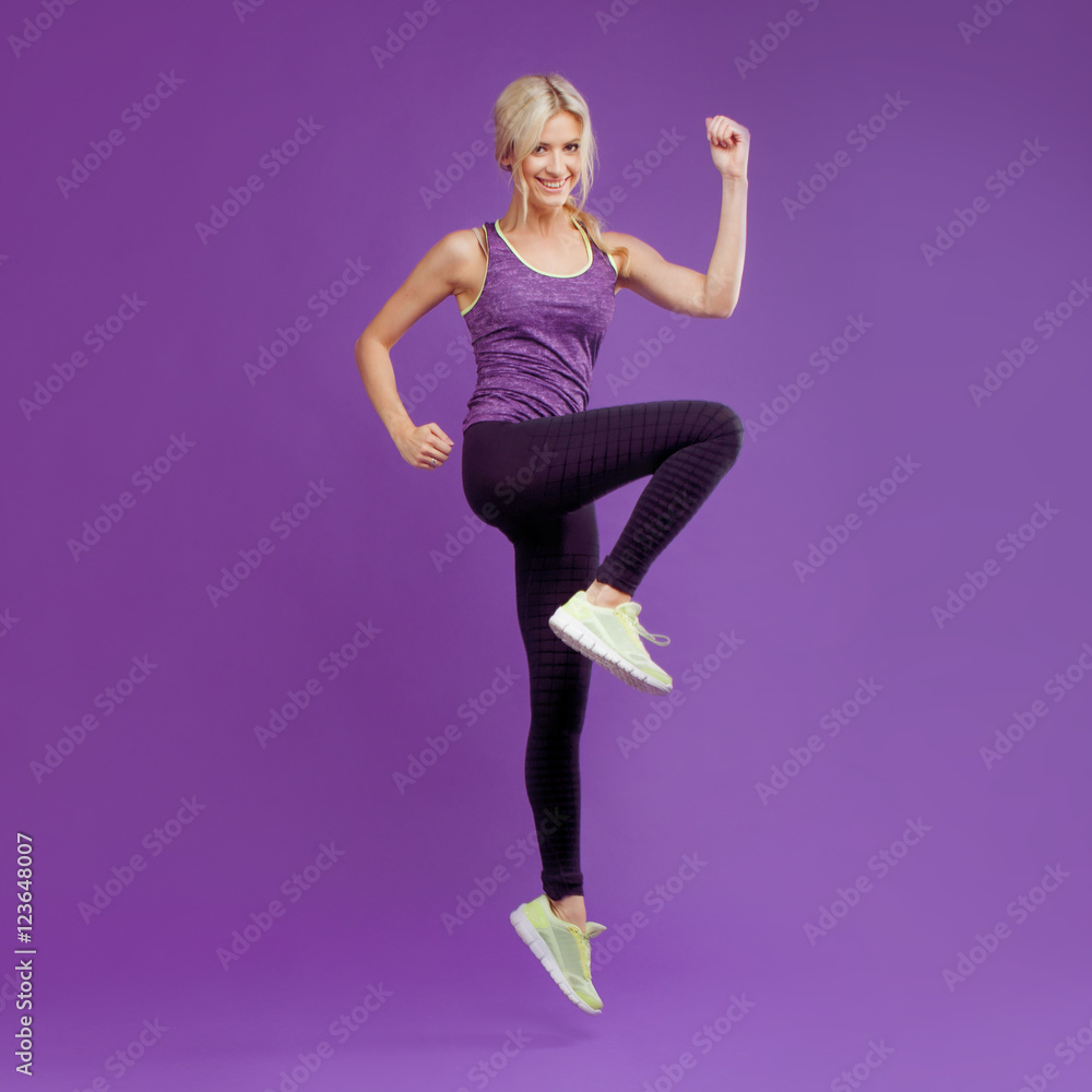 Obraz premium Beautiful young girl in a pose runner. Studio background, purple