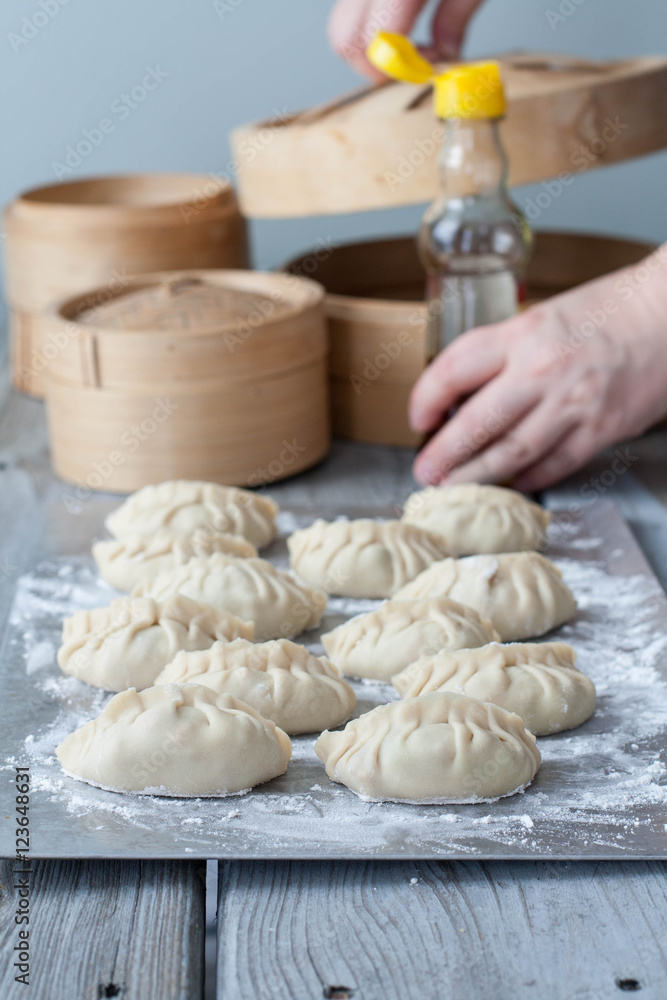Fototapeta premium The process of making Asian dumplings. Female hands in the background 