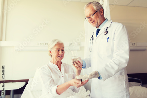 doctor giving medicine to senior woman at hospital