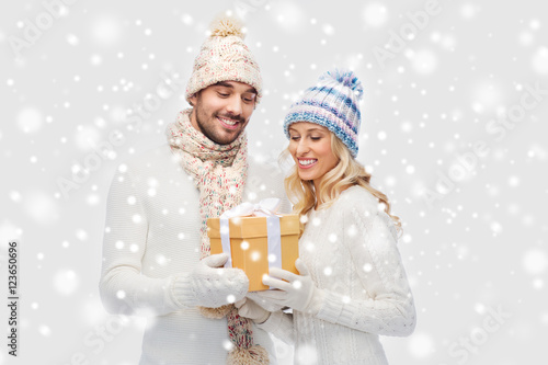 smiling couple in winter clothes with gift box