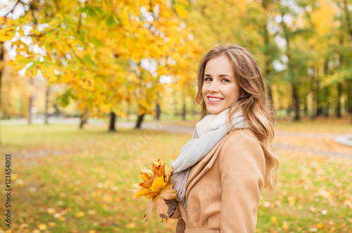 beautiful woman with maple leaves in autumn park