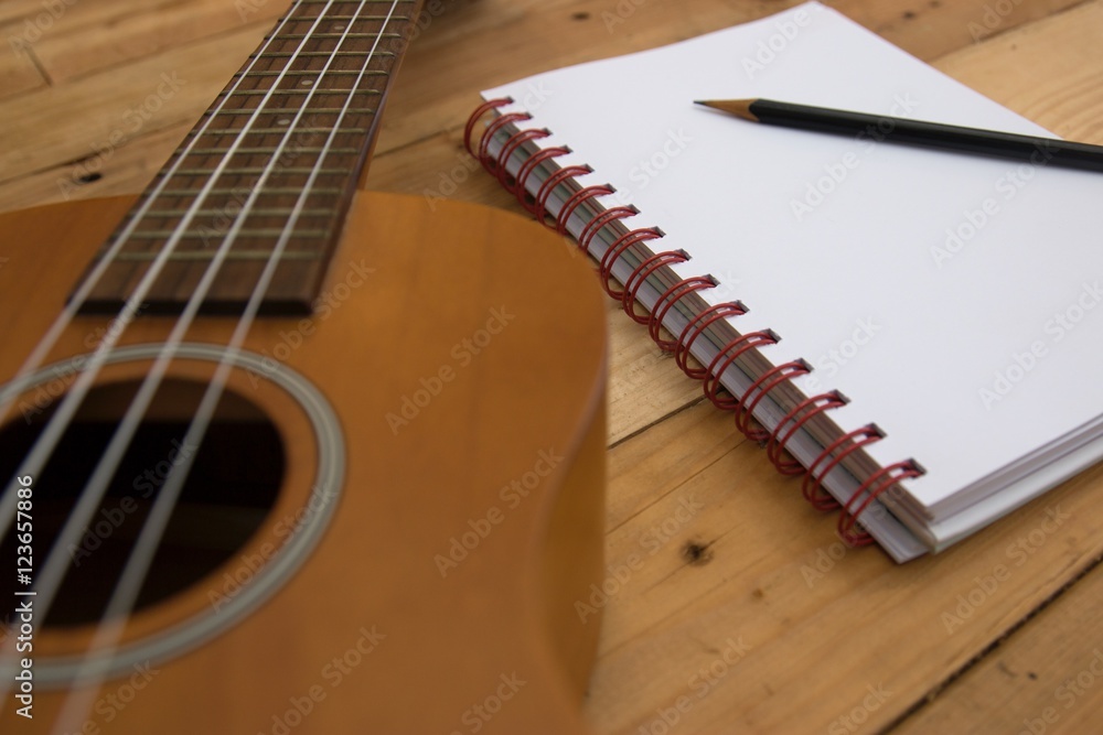 Fototapeta premium Ukulele guitar Notebook and pencil on wood table
