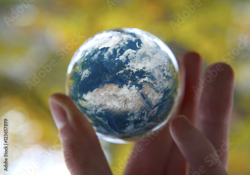 Man s hand holding the Earth with autumn Leaves background  Elements of this image furnished by NASA
