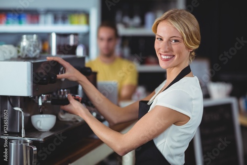 Portrait of smiling waitress making cup of coffee