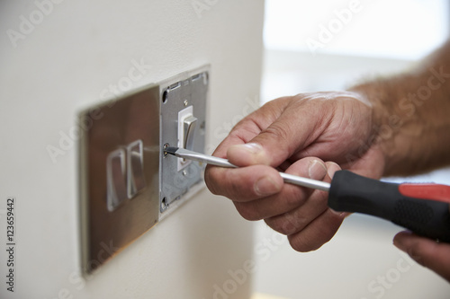 Close Up Of Electrician Repairing Domestic Light Switch