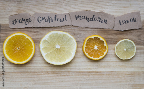 slice of lemon, white grapefruit, mandarin and orange inscribed on paper on wooden background Top view. lettering photo