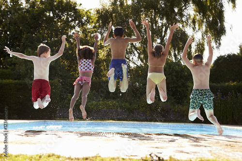 Rear View Of Children Jumping Into Outdoor Swimming Pool