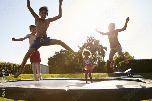 Group Of Children Having Fun Jumping On Outdoor Trampoline