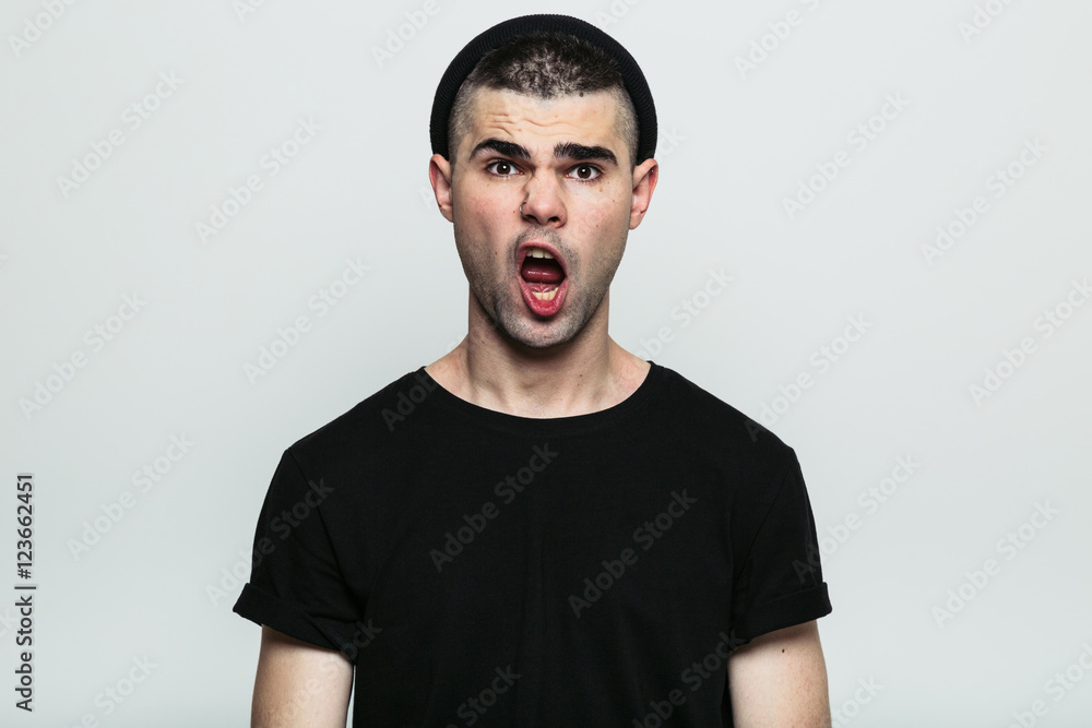 Obraz premium Male in a black t-shirt with an open mouth on a grey studio background