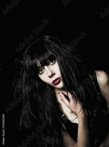 Closeup portrait of beautiful goth girl among the dark