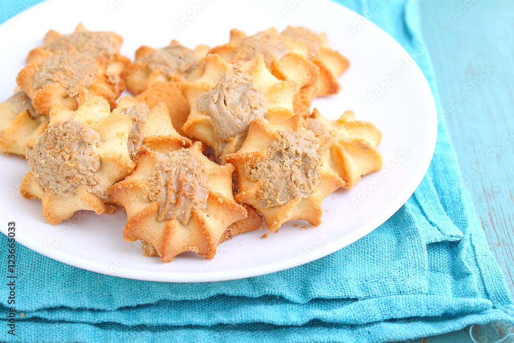 homemade cookies with halva on a white plate. Blue background homemade cookies with halva on a white plate. Blue background