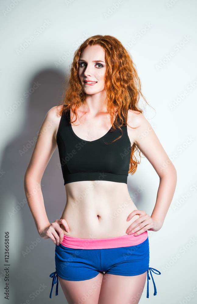 Obraz premium Studio shot: seductive ginger woman wearing shorts and shirt