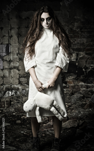 Horror style shot: scary monster girl with moppet doll in hands