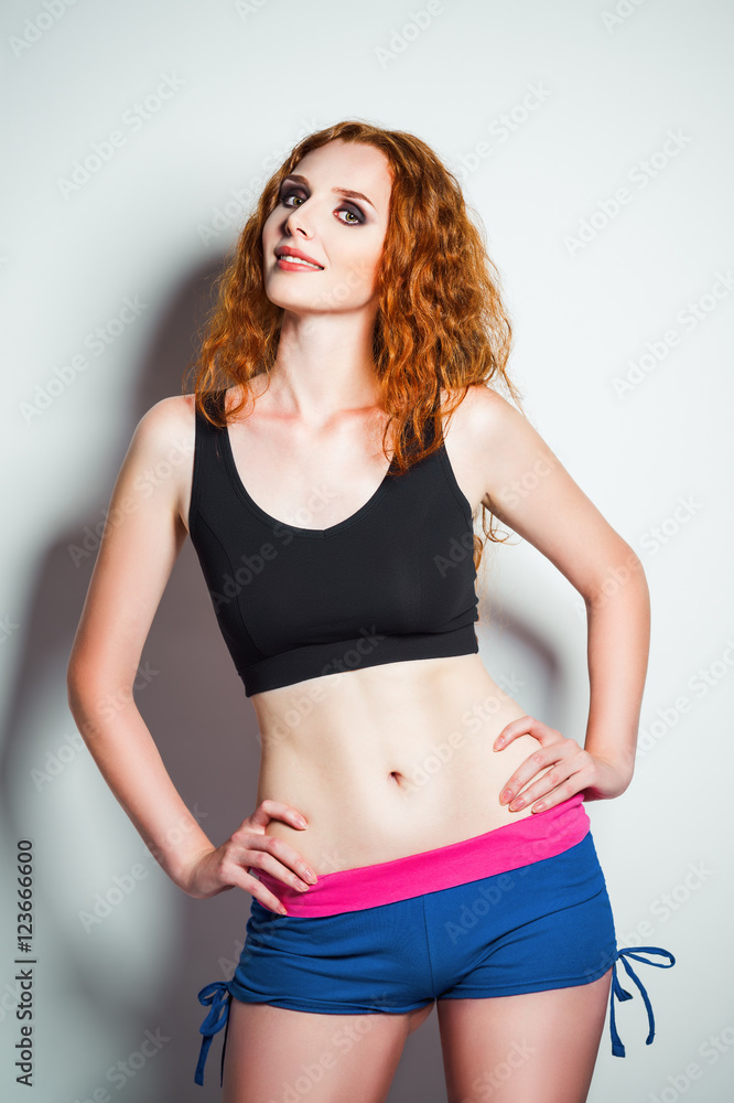 Studio fashion shot: beautiful redhead woman wearing shorts and shirt Studio fashion shot: beautiful redhead woman wearing shorts and shirt