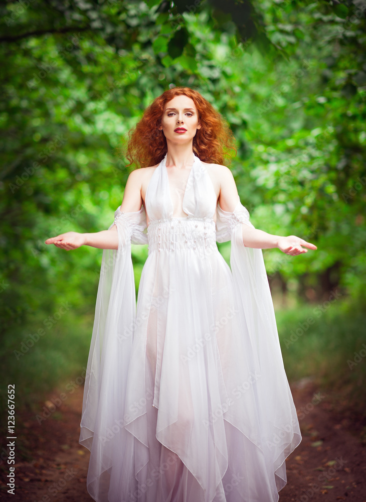 Beautiful redhead woman in white dress among trees Beautiful redhead woman in white dress among trees