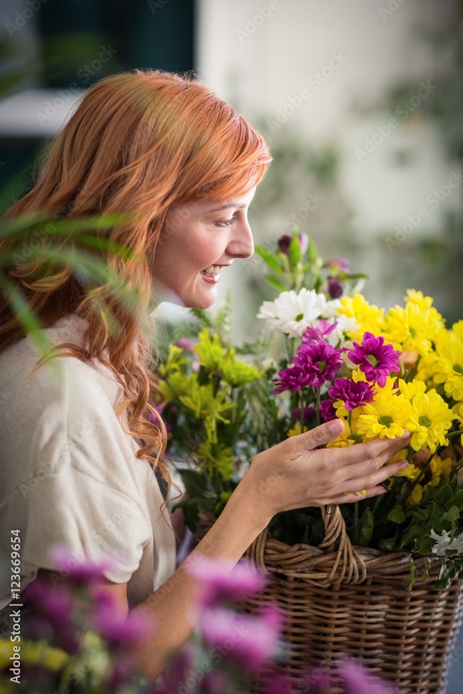 Fototapeta premium Happy female florist holding basket of flowers