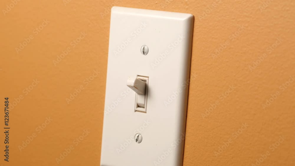 Switching ON and OFF a wall switch. Orange tan wall. Switching ON and OFF a wall switch. Orange tan wall.