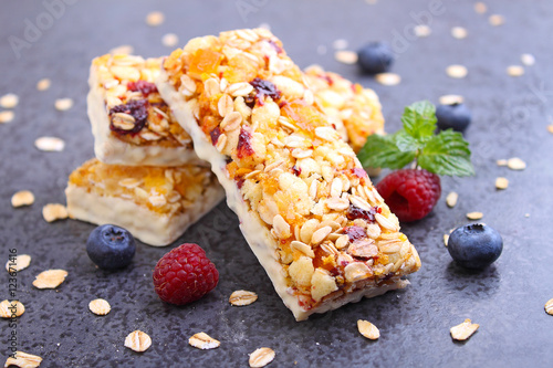 healthy snack, muesli bars with raisins and dried berries on a black background photo