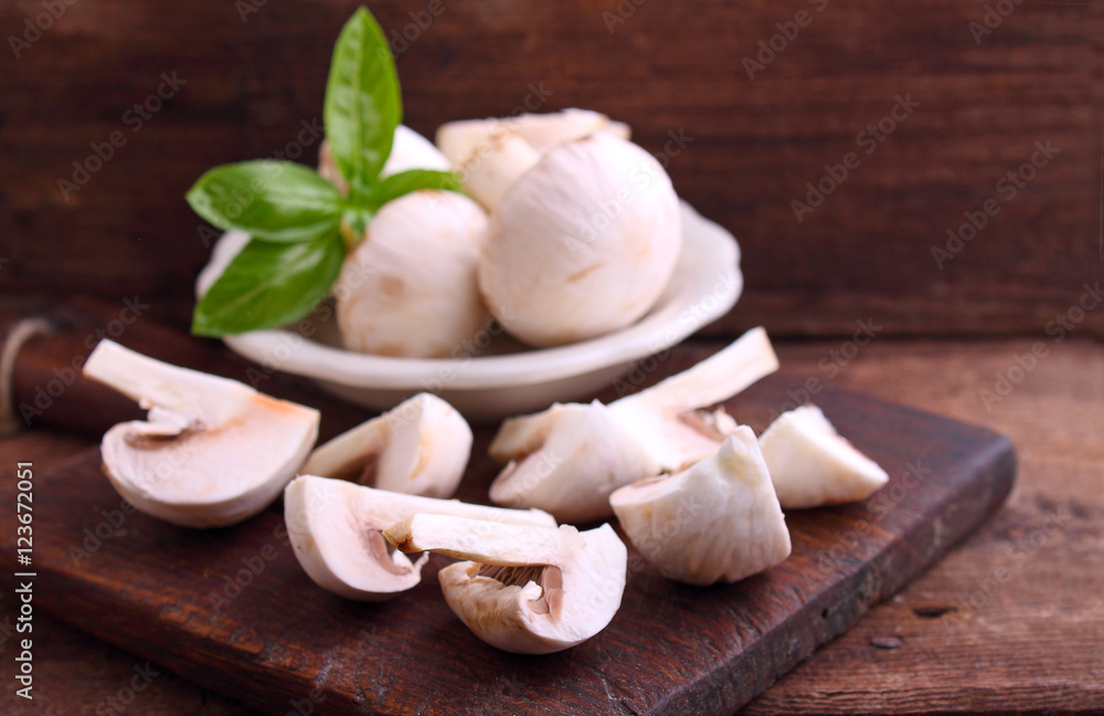 Champignon mushrooms cut into slices on old wooden board Champignon mushrooms cut into slices on old wooden board