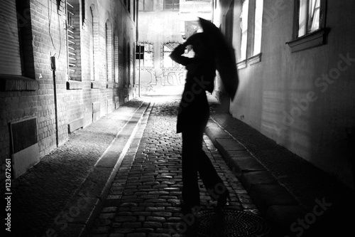 Photos Frau mit Regenschirm läuft durch eine dunkle enge Gasse bei Nacht