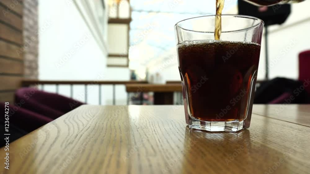 Pouring cola from the bottle into a glass Pouring cola from the bottle into a glass