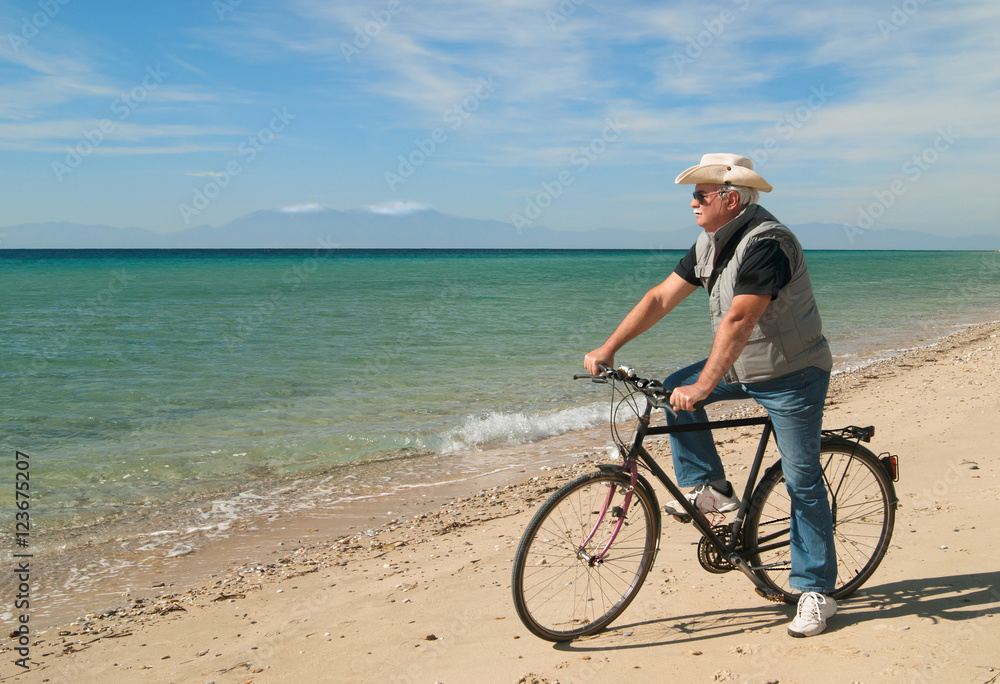 Man riding his bike along the beach in a sunny day