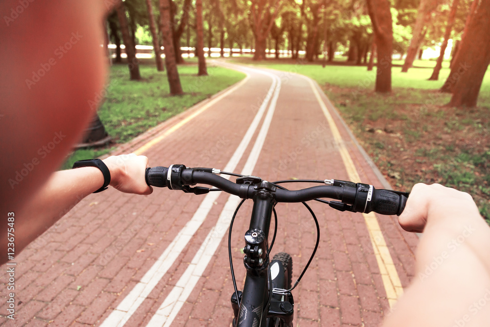 Girl riding a bicycle in the park. First-person view Girl riding a bicycle in the park. First-person view
