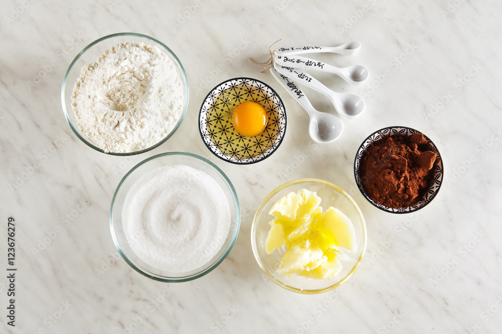 Ingredients for baking on a white marble table : flour, eggs, co Ingredients for baking on a white marble table : flour, eggs, co