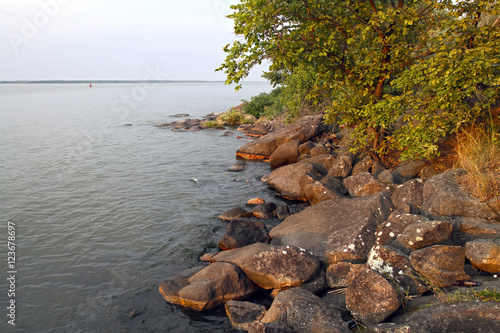 Large granite rocks on the shore of the great river in the summer. Beautiful sunset on the river quiet summer evening