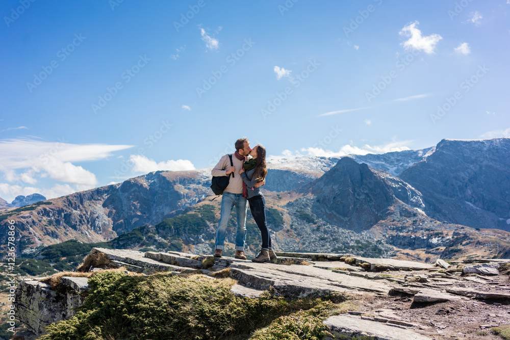 Frau und Mann küssen sich verliebt im Gebirge beim Wandern