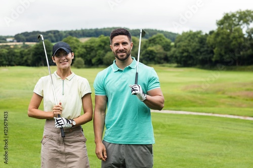 Couple standing with golf club in golf course