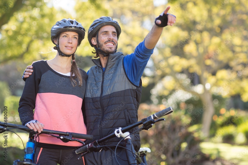 Biker couple with mountain bike pointing in distance Biker couple with mountain bike pointing in distance