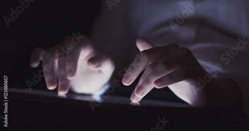 young female teen using tablet pc in the dark environment very shallow focus