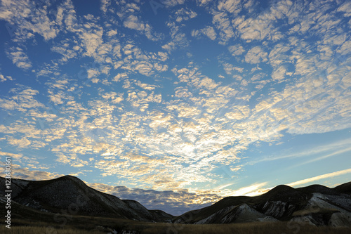 Mountain peaks and blue sky. Clouds at dawn in sun. Landscape natural background.