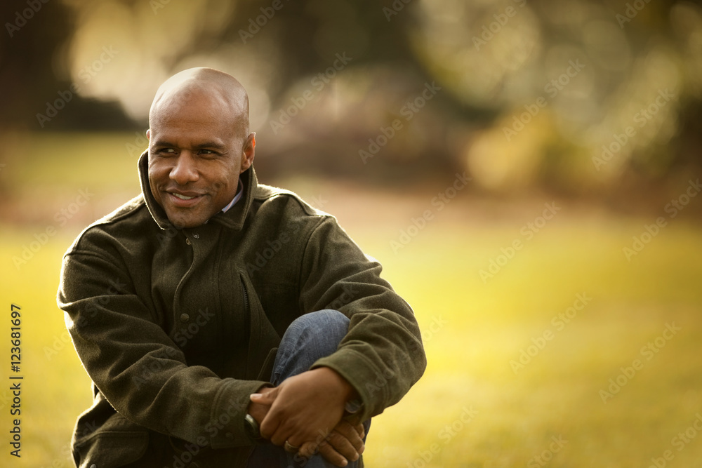 Smiling mid adult man sitting in a park. Smiling mid adult man sitting in a park.