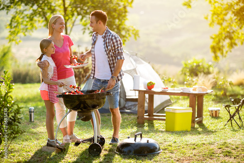 smiling parent grilling meat with daughter.