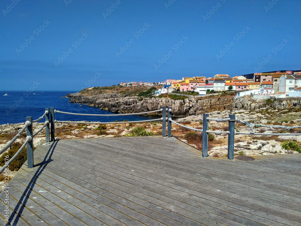View to houses near ocean from wooden road in Peniche