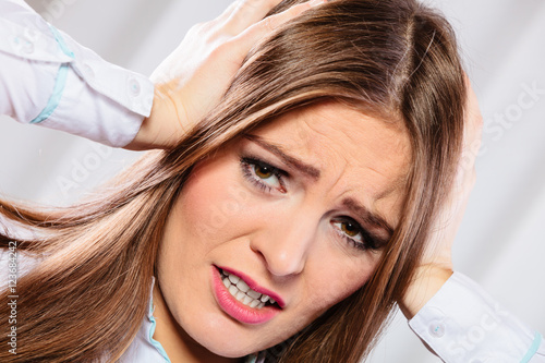 stressed woman in white shirt with headache