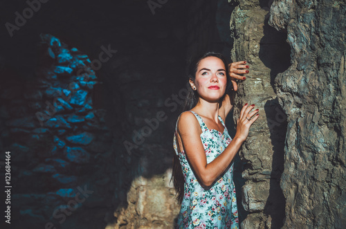 Portrait of young romantic woman with long hair, red lips and manicure in white dress flowers. Attractive girl in Stari Bar old fortress, Montenegro. Brunette female walks around castle, the magic