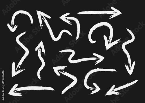 Set of white arrows painted with a brush. Grunge. Isolated on black background.