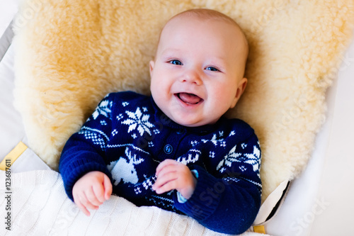 Fotografie Little baby in nordic sweater on sheepskin muff