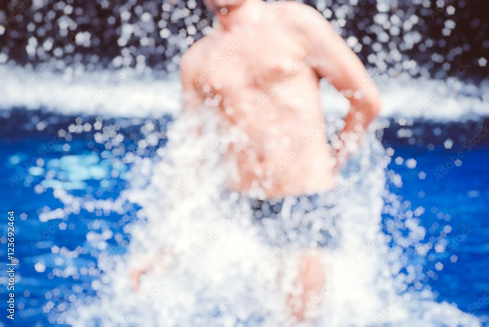 Handsome muscular guy jumping from water blurred bokeh background