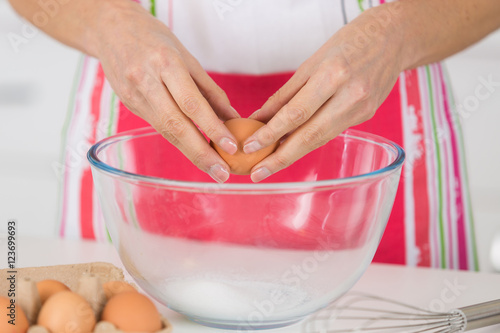 close-up of woman cracking egg for pastry