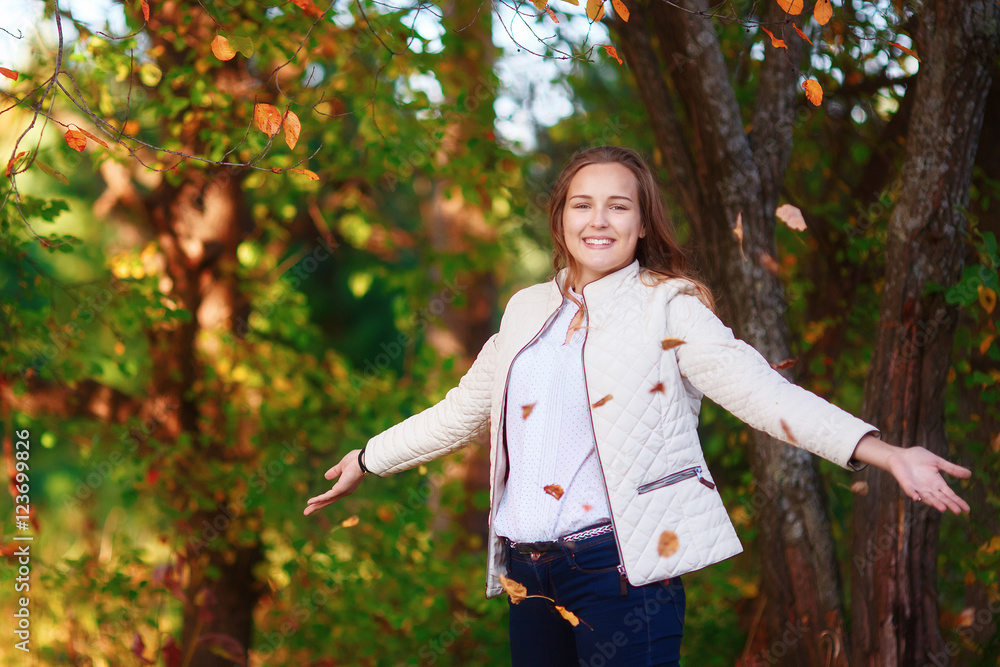 Young beautiful teenager girl tosses colorful autumn leaves in park Young beautiful teenager girl tosses colorful autumn leaves in park
