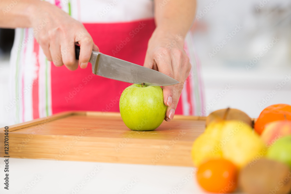 close-up on mature female hands slicing apples on chopping board close-up on mature female hands slicing apples on chopping board