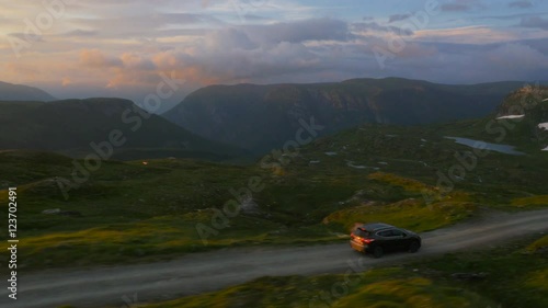 Aerial Shot of Car Moving on Curvy Mountain Road in Norway. Beautiful Mountain Landscape on Background.