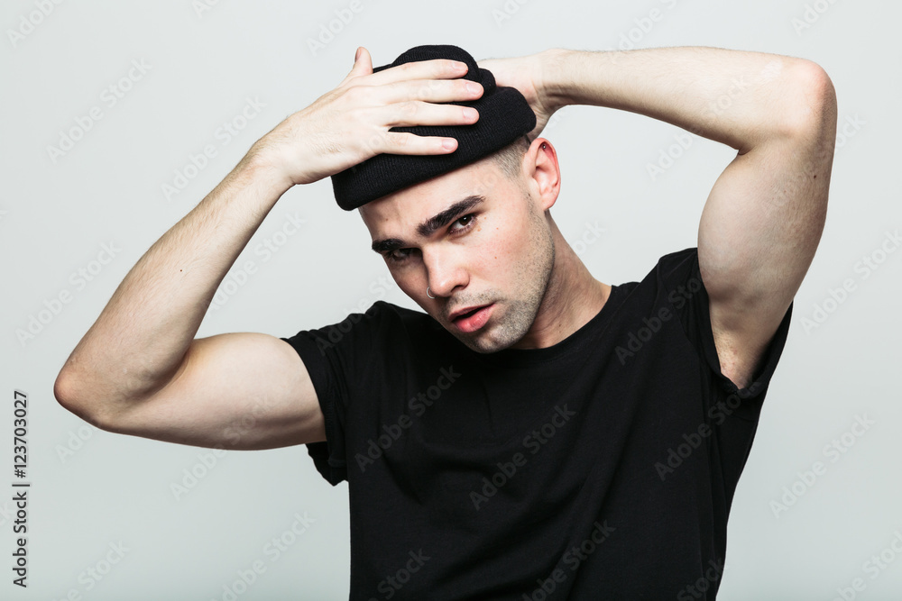 Studio portrait of handsome man putting his hat on, while looking at camera frowningly on white background. Studio portrait of handsome man putting his hat on, while looking at camera frowningly on white background.