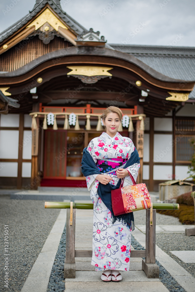 Woman dressed in traditional japanese costume walking under tori