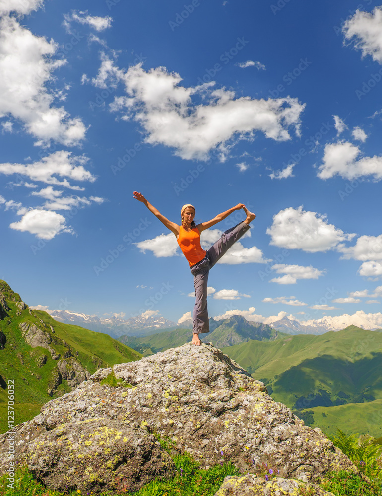 Young woman exercises yoga in the mountains